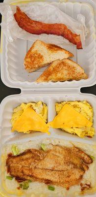 Catfish, grits, eggs with cheese, toast, n a slice of bacon.