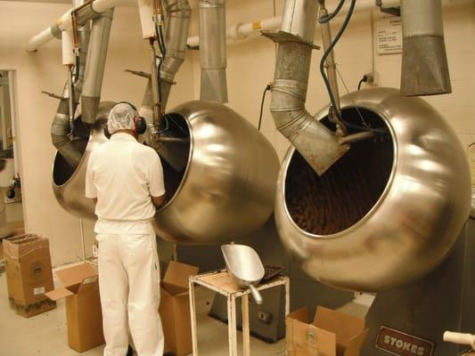 Panning - the process of evenly coating roasted mac nuts with chocolate.
