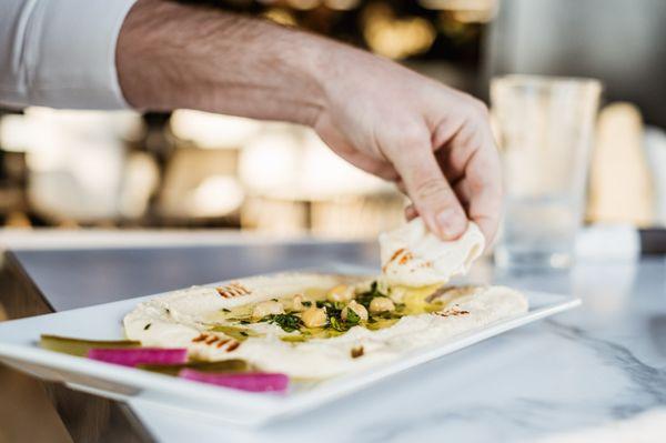 Behold the perfect harmony of hummus and warm pita bread. With every dip, a burst of creamy delight awaits.