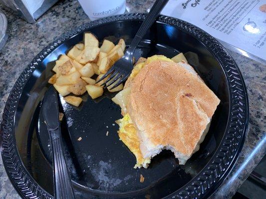 A turkey and Swiss breakfast sandwich with a side of home fries.