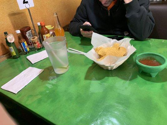 Table with chips and salsa and assortment of hot sauces