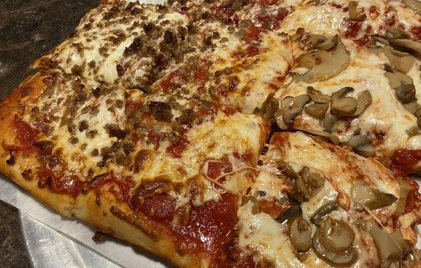 Half sheet of pizza with sausage and mushrooms
