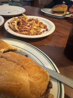 Philly Cheese Steak, bacon cheese fries and a big ol hamburger in background.