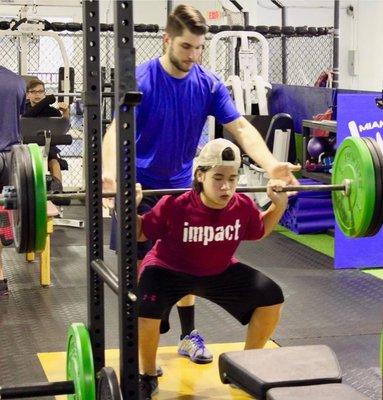Dr. Ramirez teaching a young adult proper squat form