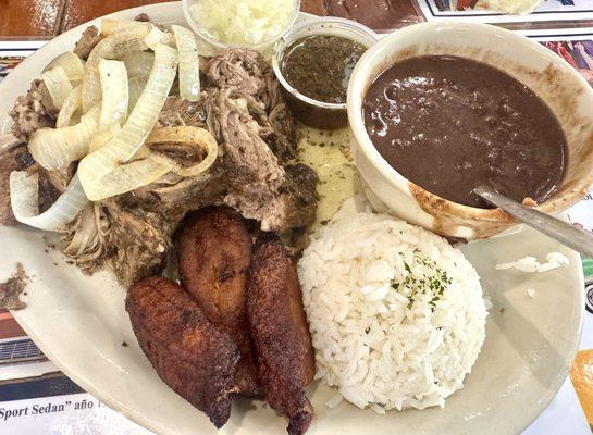 Lechon Asado, one of their specialties, served with black beans, rice, and plantain