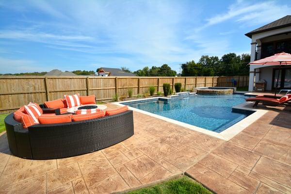 Geometric swimming pool with built-in ledges, spillover spa, and fountain