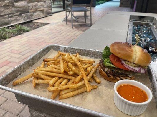 Cheeseburger and fries with side of hot sauce