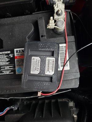 Tracking device connected to side of battery.