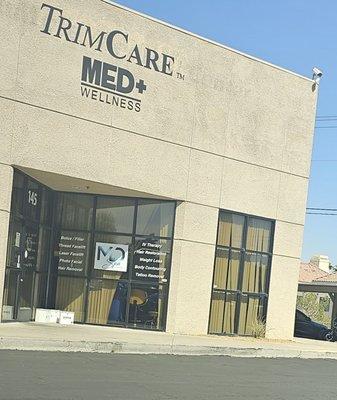 Dirty exterior with medical waste boxes at the entrance floor. Broken blinds, weeds, a view into the medical suite.