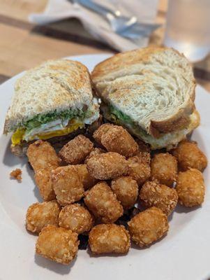Breakfast sandwich ( sausage, egg cheese and avocado) with tater tots