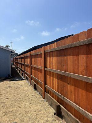 Redwood picket fence with pressure treated retainer