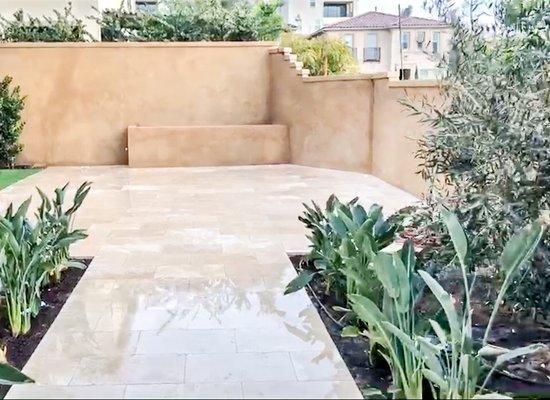 Travertine tile flooring, smooth coat stucco wall finish, birds of paradise, and custom fir pit.