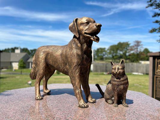 Bronze life size dog and cat atop cremation niches in Pet Sanctuary garden.