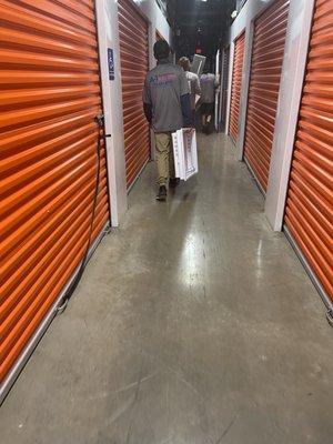 Two of three guys carrying one thing instead of using cart or carrying two things at a time