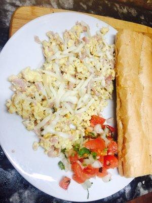 Revuelto de jamón y queso acompañado de una tostada con mantequilla y un café con leche