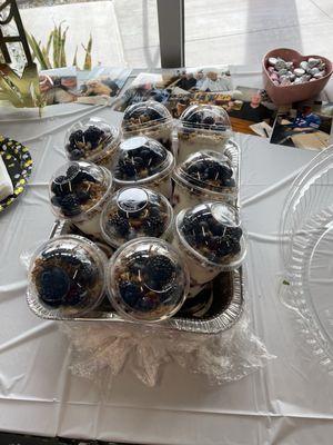 Yogurt parfaits topped with granola & honey in bin with ice.