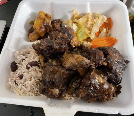 Oxtail on a bed of rice and beans, with a side of plantains and mixed vegetables (cabbage, carrot, bell pepper).