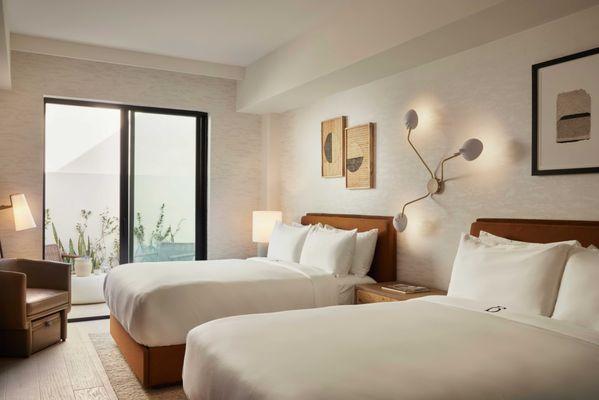 The Bower's double room exudes comfort with soft neutral tones, warm lighting, and a private terrace for a peaceful retreat.