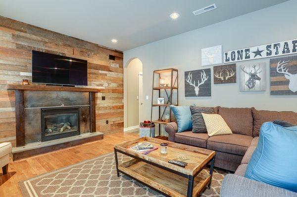 Barnwood wall with steel fireplace with a poured concrete hearth and reclaimed mantel