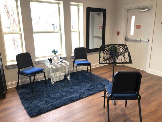 A small instrument trial room with three chairs and sheet music stand