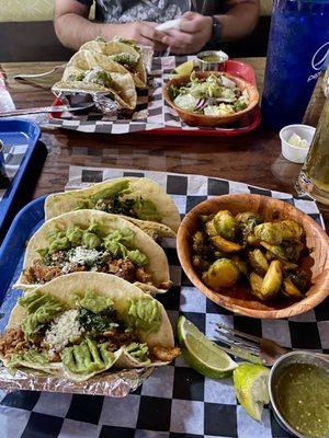 Smoked chicken tacos with hot honey Brussels sprouts in the foreground and pork belly tacos with layered salad in the background