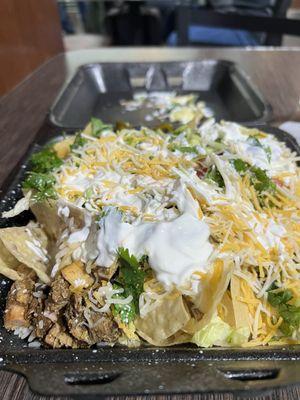 Chicken nachos with sour cream, cheese, onions, black beans, rice, cilantro, and jalapeños