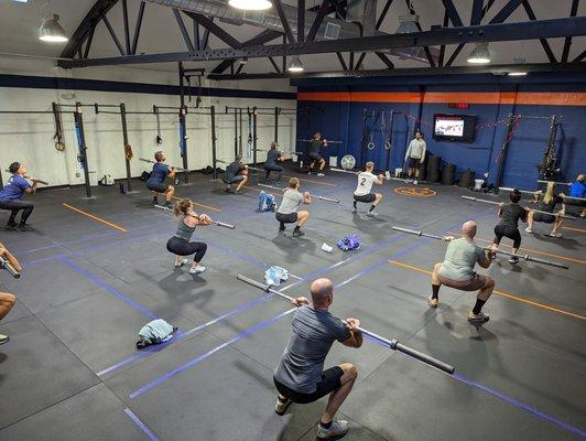 Coach Adrian leads the class through a warmup to get them ready for squats