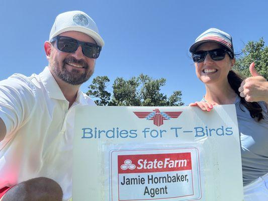 Matt & Jamie pose in front their hole sponsor sign for a local school fundraiser