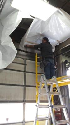 Hanging plastic sheeting on ceiling to brighten up an automotive shop