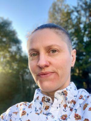 A headshot portrait of Nik Kurtz, a white queer trans non-binary person with eyes directed at the camera. They offer Esalen Massage.