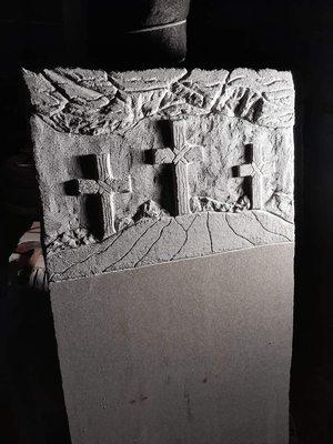 A granite headstone which features three crosses being worked on.