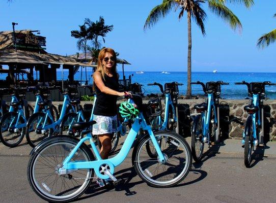 There is a booth across from the station where you can borrow a helmet for free. The bikes also have locks on board.