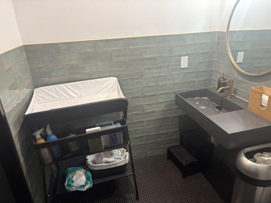 Restroom equipped with changing table, spare diapers, and other essentials.