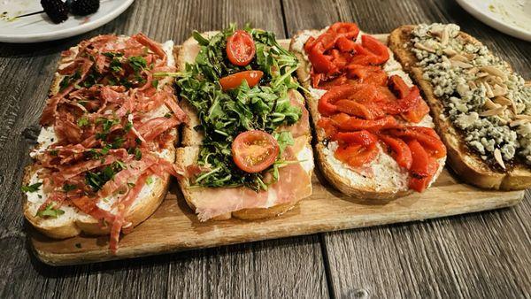 Bruschetta board: spicy soppressata, ricotta and parsley; Prosciutto, arugula balsamic; roasted red pepper; fig jam, Gorgonzola crumbles