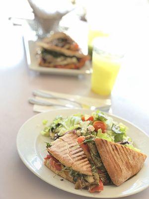 An All Natural Fresh Pineapple drink Chicken Pesto Panini with a side of Greek Salad