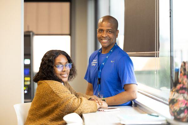 A student connects with a supportive staff member inside a bright, modern campus space.