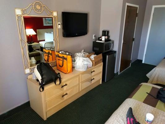 Four large drawers for clothes, fridge with freezing section, microwave, and coffee maker. TV is small.