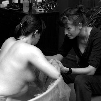Renee holding hands with a birth doula client in a tub