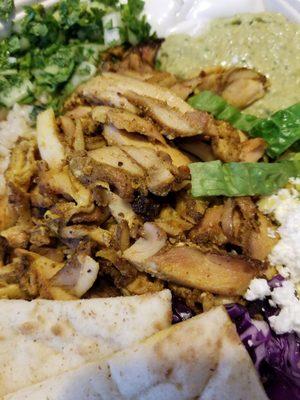 Chicken shawarma bowl with cilantro hummus, cous cous, lettuce, cabbage, feta cheese, and onion with cilantro.