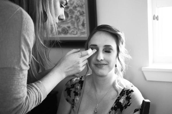 Ivy Jacobs applying false eyelashes to a bridesmaid