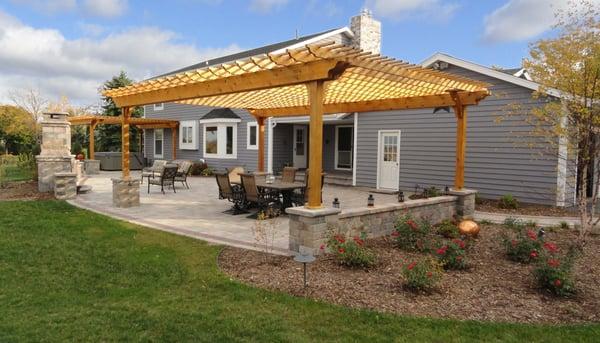 Large outdoor living space with two pergolas, seat walls, fire place, outdoor kitchen and landscape lighting.