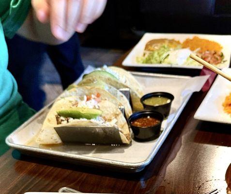 Carnitas tacos, served with beans, rice, sour cream, pico, guac, lettuce, avocado on top salsa, and tomatillo sauce. an absolute Yum.