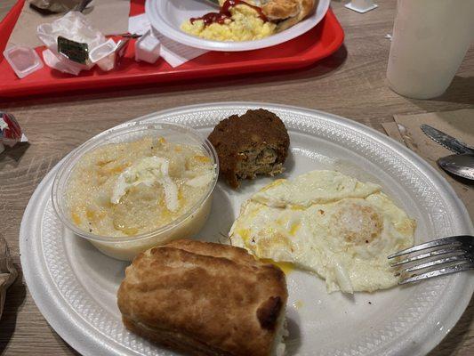 Salmon croquette, sunny side up eggs, grits with cheese, and a biscuit