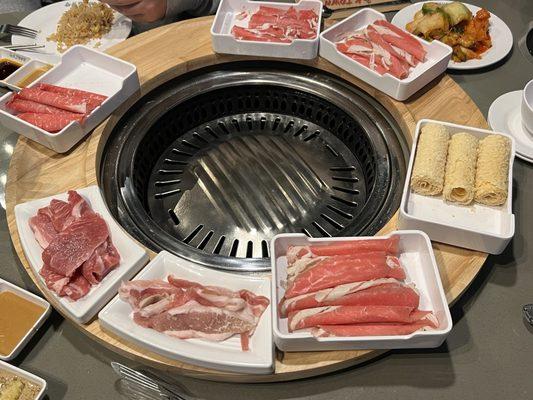 Meats and fried tofu set around the grill