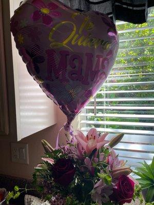 Flowers are wilted. The balloon is in Spanish. I'm not sure what it says.