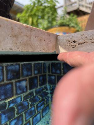 The 2 inch gap between the tile around the pool and the edge. All pool water backwashes behind the pool and they won't come fix it.