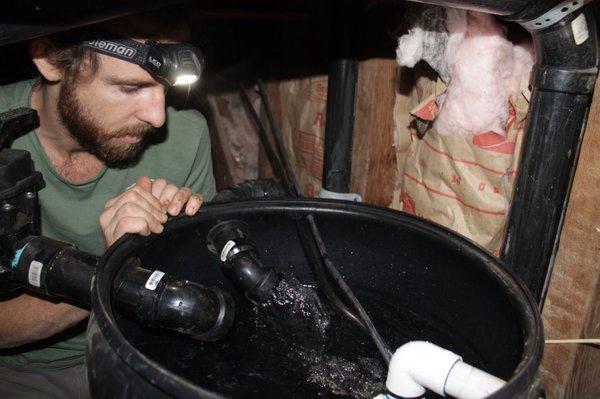 A greywater pump and surge tank located in the crawl space beneath a customer's house.