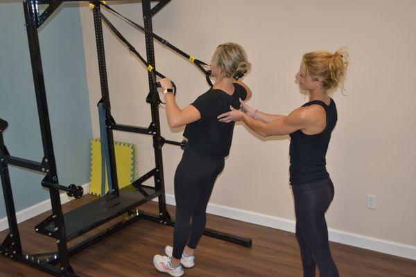 Trainer Julia is working with TRX bands and a client strengthening back muscles while engaging core muscles for stability at Pilates LBK
