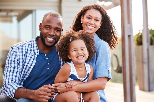 A radiant young Black family enjoying the day outdoors with infectious smiles