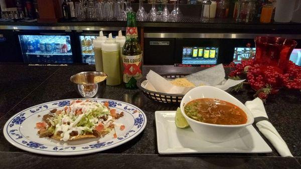 On the left,a steak tostada, on the right, goat soup,(chivo) homemade tortillas, various sauces hot, mild, avocado,house made salsa.